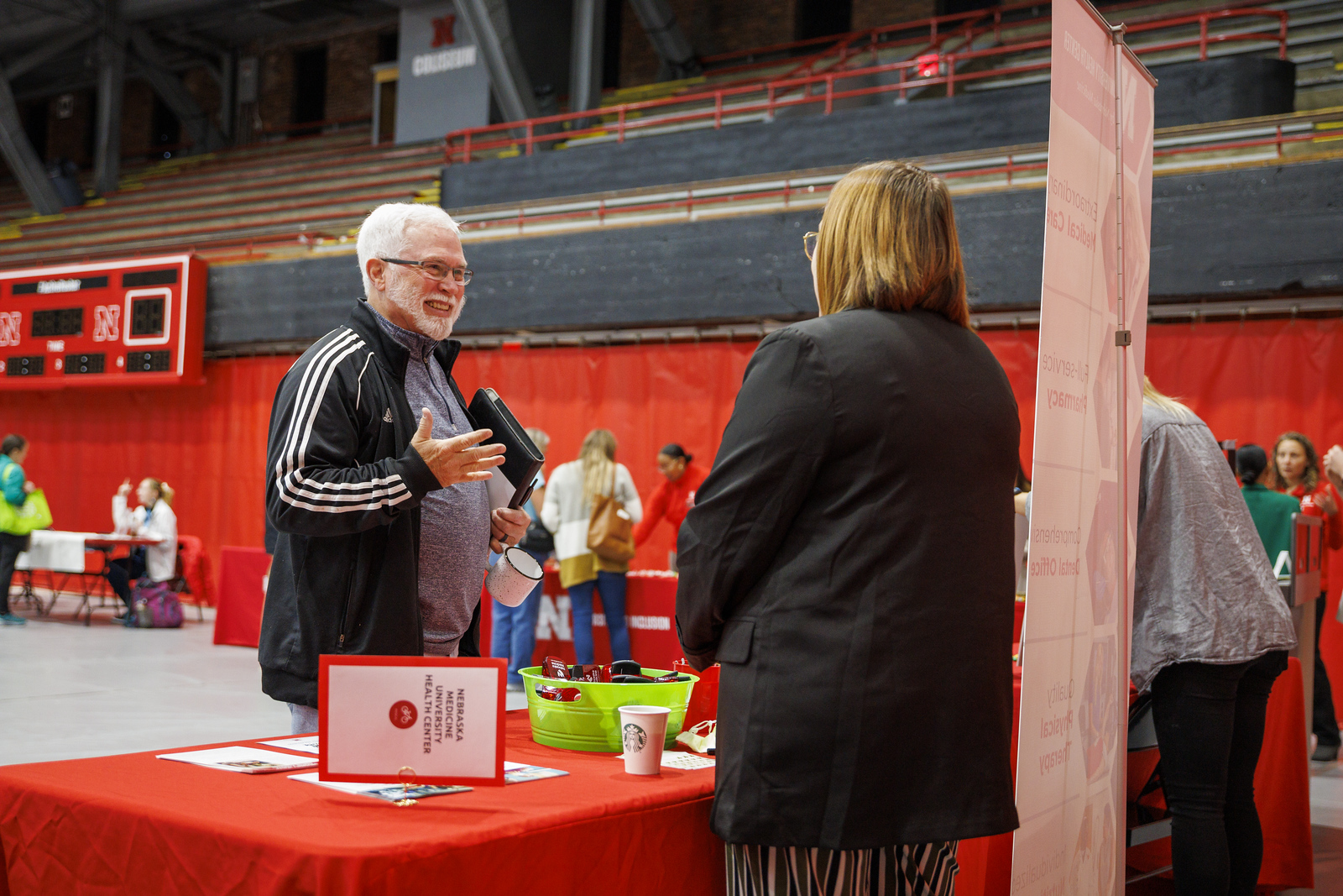 An employee stops at a booth at a campus wellness fair