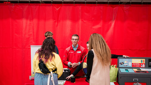Professional speaking with two employees at booth