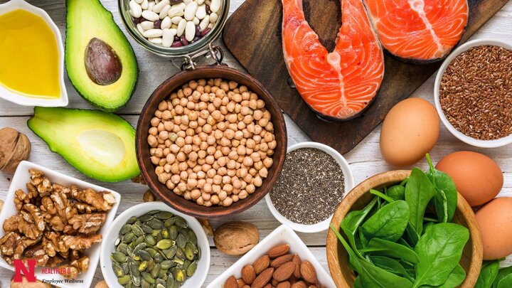 Food on a table; avocado, chickpeas, spinach, almonds, eggs, walnuts, oils, chia seeds, salmon