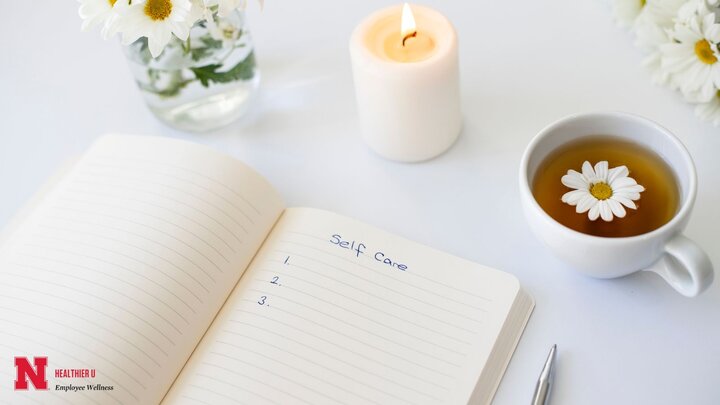 Open notebook, cup of tea with a flower floating, white candle with a flame