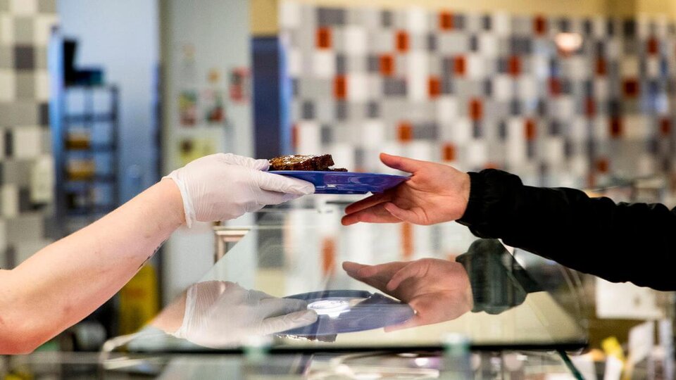 One person handing a plate of food to another over a counter