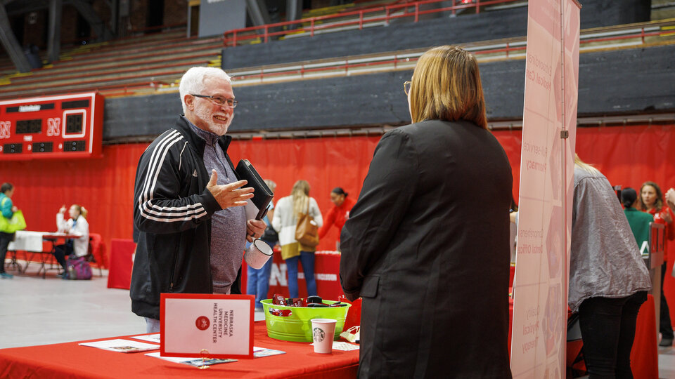 An employee stops at a booth at a campus wellness fair