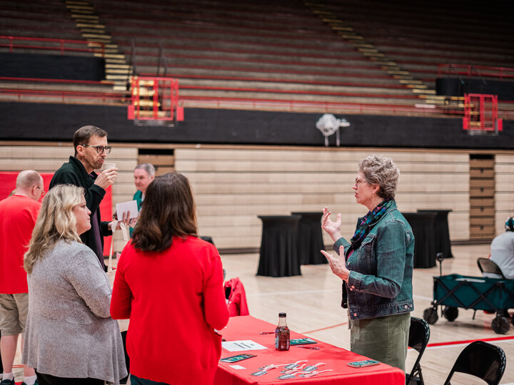 Three employees speaking with a vendor at the wellness fair
