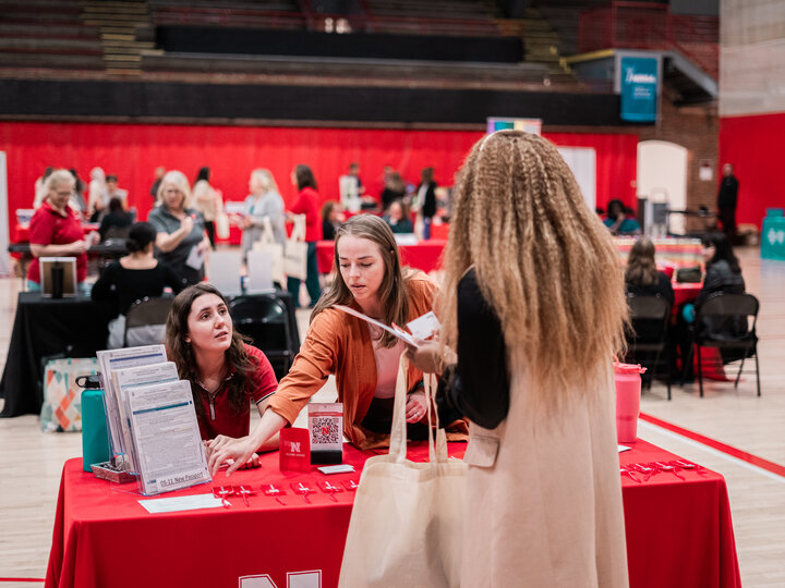 Two vendors pointing to their resources at their booth table and speaking with an employee at the wellness fair
