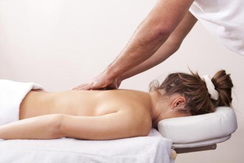 Woman on massage table with hands on shoulders